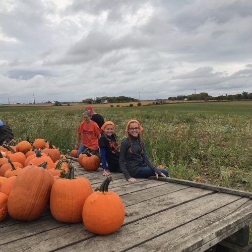 Girls Sitting on Trailer with Pumpkins