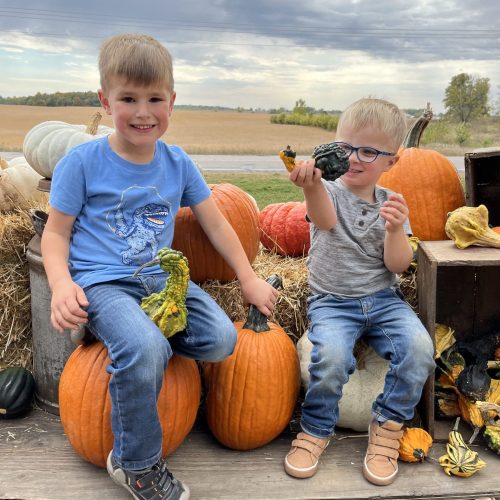 Two Young Boys Playing with Gourds and Sitting on Pumpkins